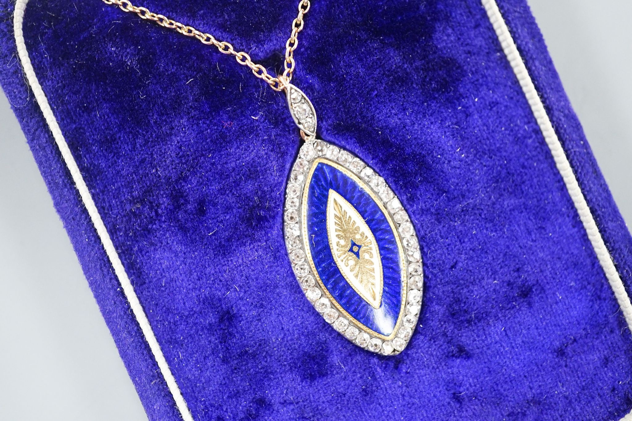 An early 20th century yellow metal, two colour enamel and diamond set navette shaped pendant, 32mm, on a yellow metal chain, 47cm, gross weight 6.9 grams.
